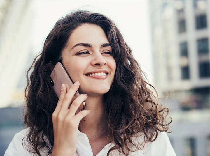 A smiling brunette woman talking on the phone